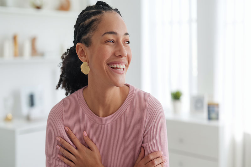 Femme souriante dans un cadre familier, symbolisant le soulagement après un dépistage précoce réussi.