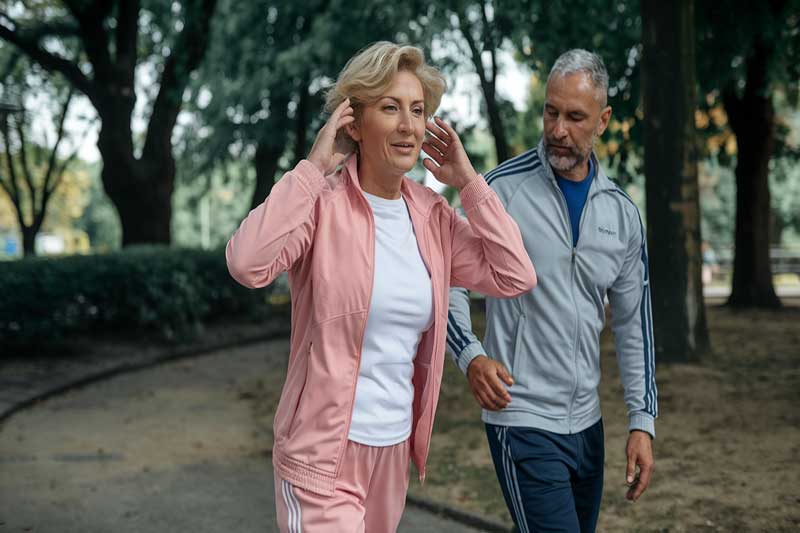 Femme d'âge mûr faisant de l'exercice dans un parc, symbolisant un mode de vie actif pour une meilleure santé cardiaque après la ménopause