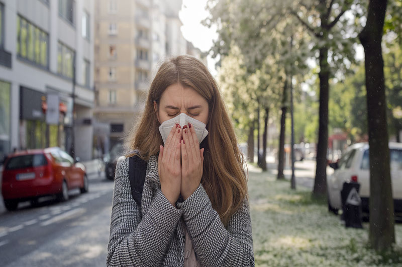 Personne souffrant de sinusite, touchant son visage au niveau du front et du nez pour illustrer la douleur liée à l'inflammation des sinus.