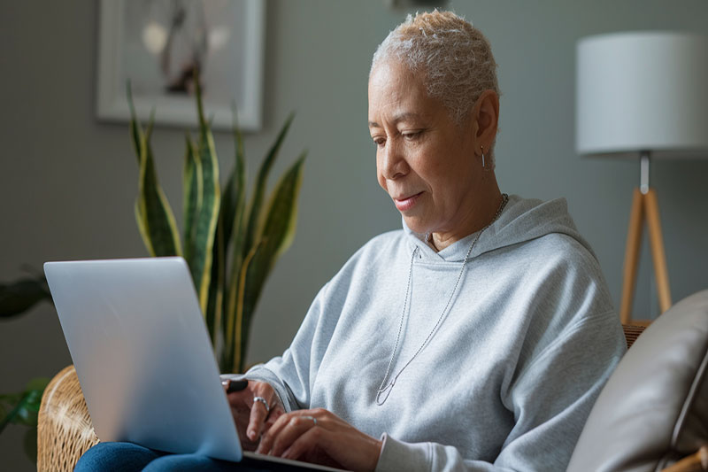 Patient ou aidant consultant des ressources de soutien en ligne sur le cancer depuis un ordinateur portable.