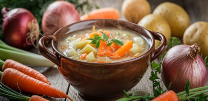 Bol de soupe maison avec des légumes frais sur une table en bois dans une ambiance hivernale.